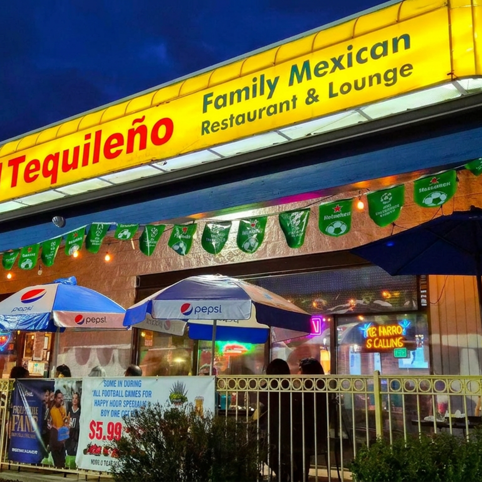 El Tequileño Family Mexican Restaurant & Lounge storefront lit at night, with Pepsi umbrellas, festive banners, outdoor seating, and patrons inside.