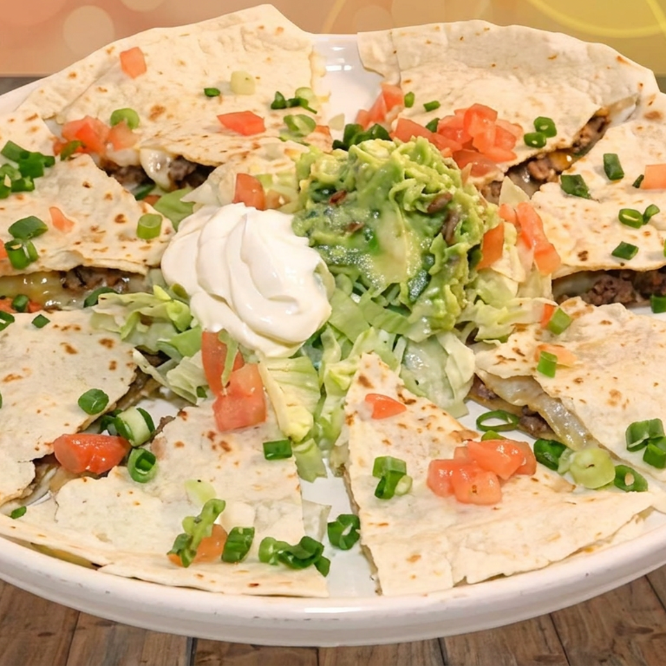 Large platter of quesadilla wedges topped with diced tomatoes and green onions, served with lettuce, guacamole, and sour cream.